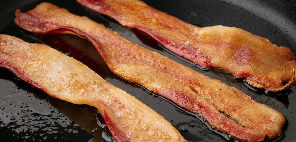Hooray Foods plant-based bacon cooking in the pan